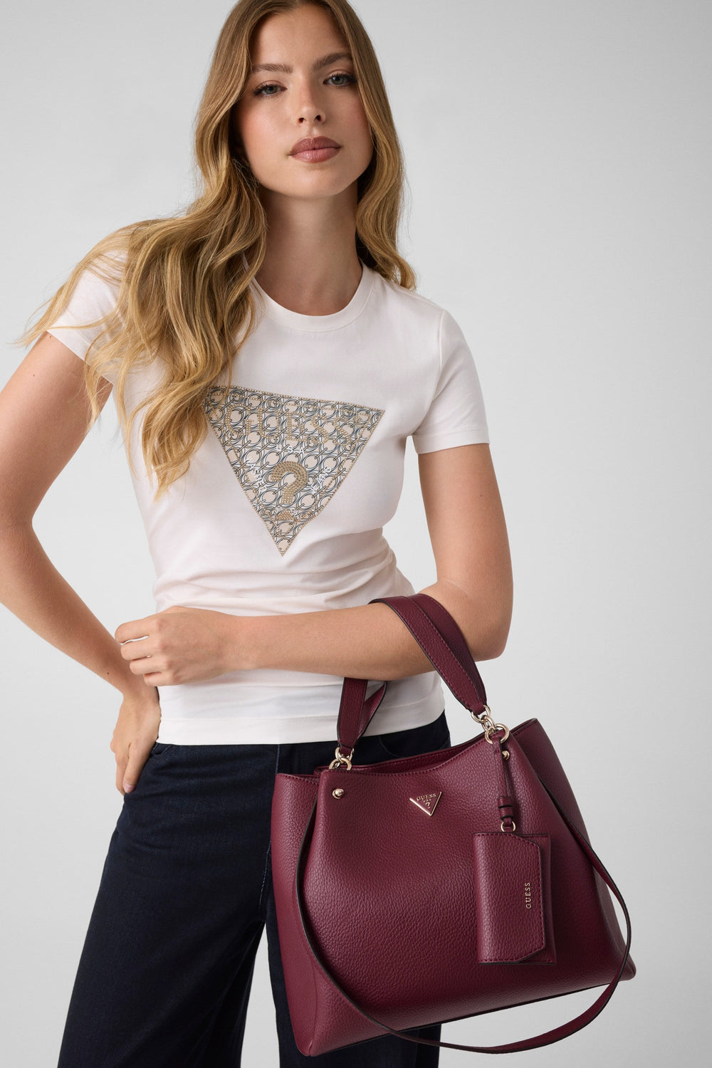Guess rode Lorella-shopper in de hand, met een wit T-shirt en een zwarte broek.