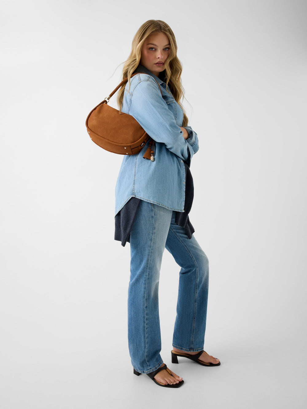 Guess brown hobo bag Danya Hobo Shoulder over the shoulder, with a light blue shirt and jeans.