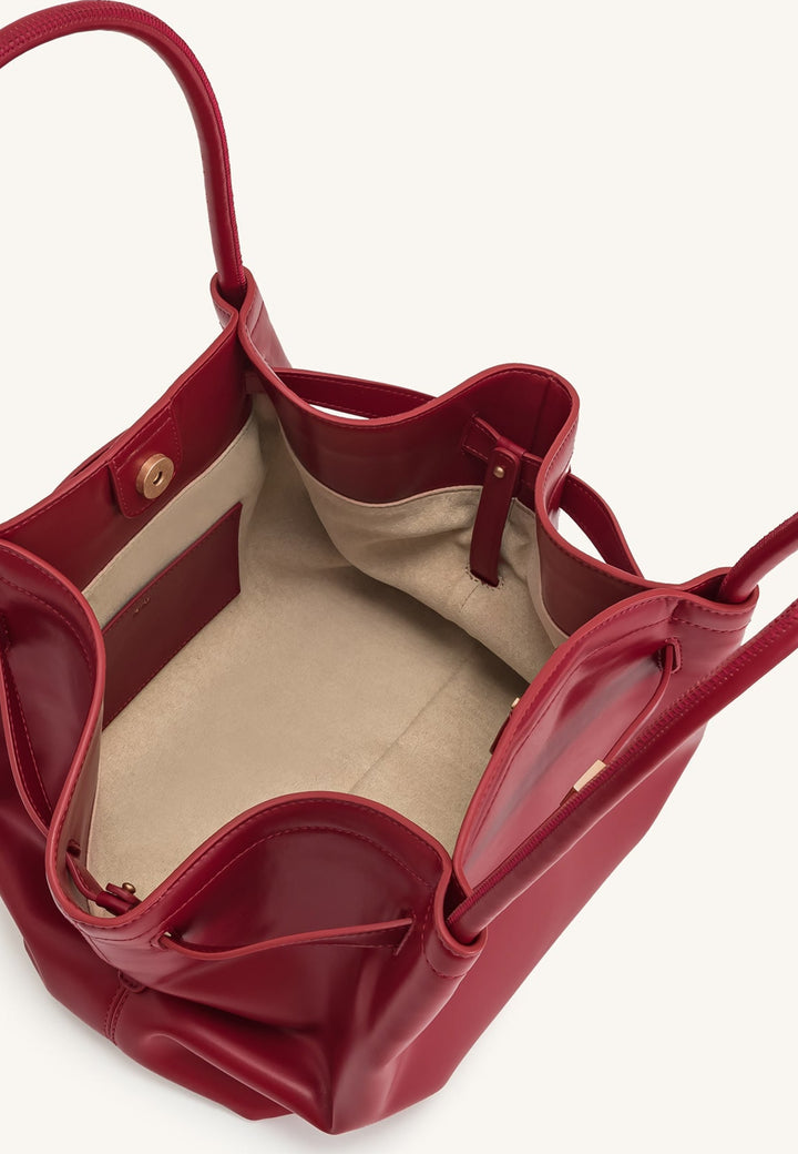 Intérieur d'un sac cabas JW PEI Hana rouge claret, avec une poche intérieure et une fermeture magnétique visible.