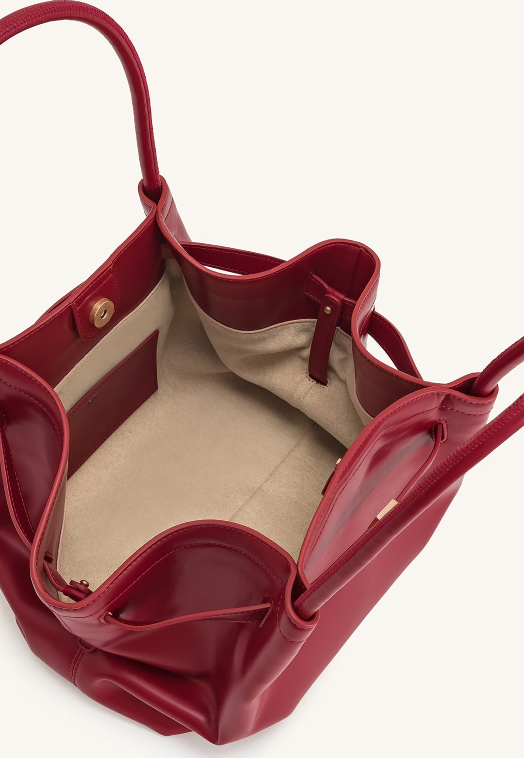 Intérieur d'un sac cabas JW PEI Hana rouge claret, avec une poche intérieure et une fermeture magnétique visible.