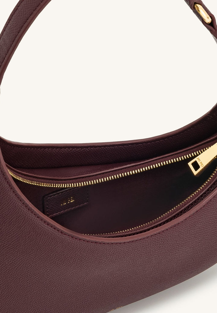 Intérieur d'un sac bandoulière JW PEI Harlee Claret avec fermeture éclair dorée et étiquette de marque visible
