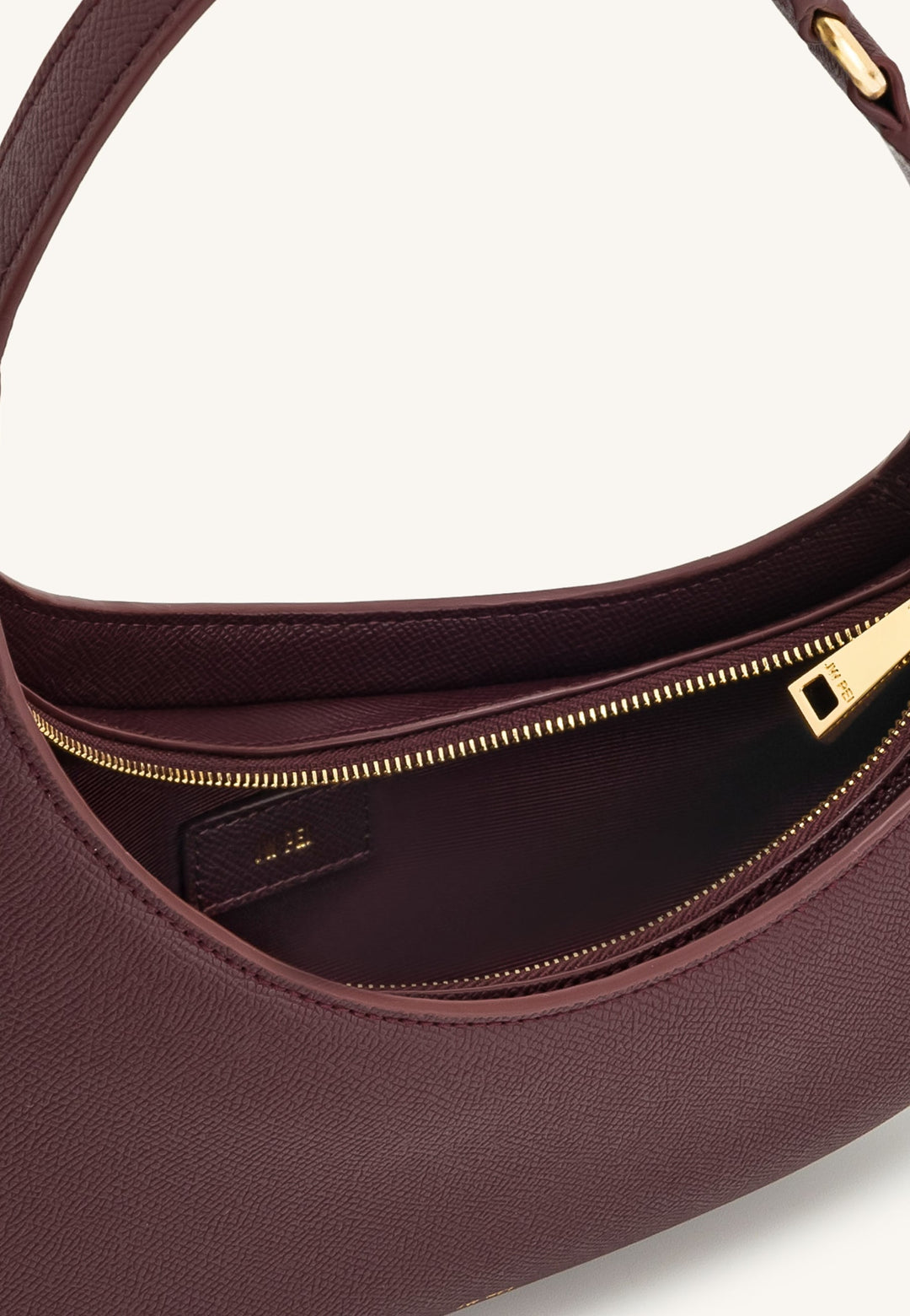 Intérieur d'un sac bandoulière JW PEI Harlee Claret avec fermeture éclair dorée et étiquette de marque visible