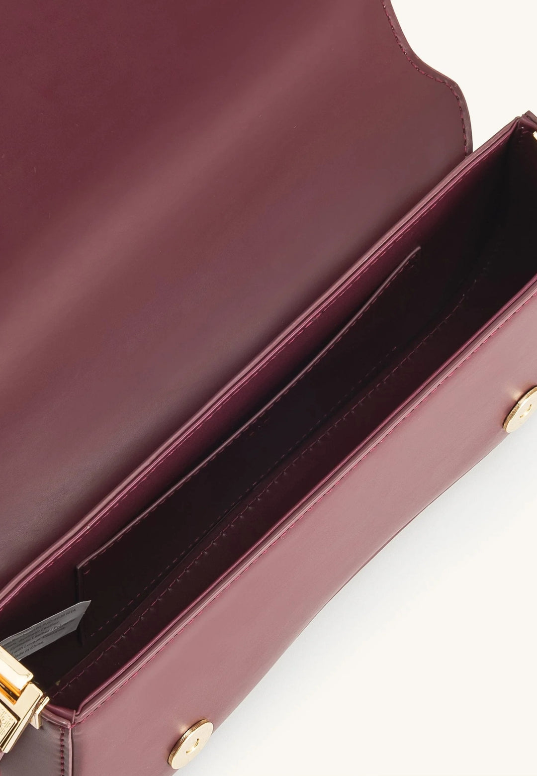 Intérieur d'un sac bandoulière JW PEI Joy Deep Claret en simili cuir bordeaux, avec une poche intérieure et une étiquette.