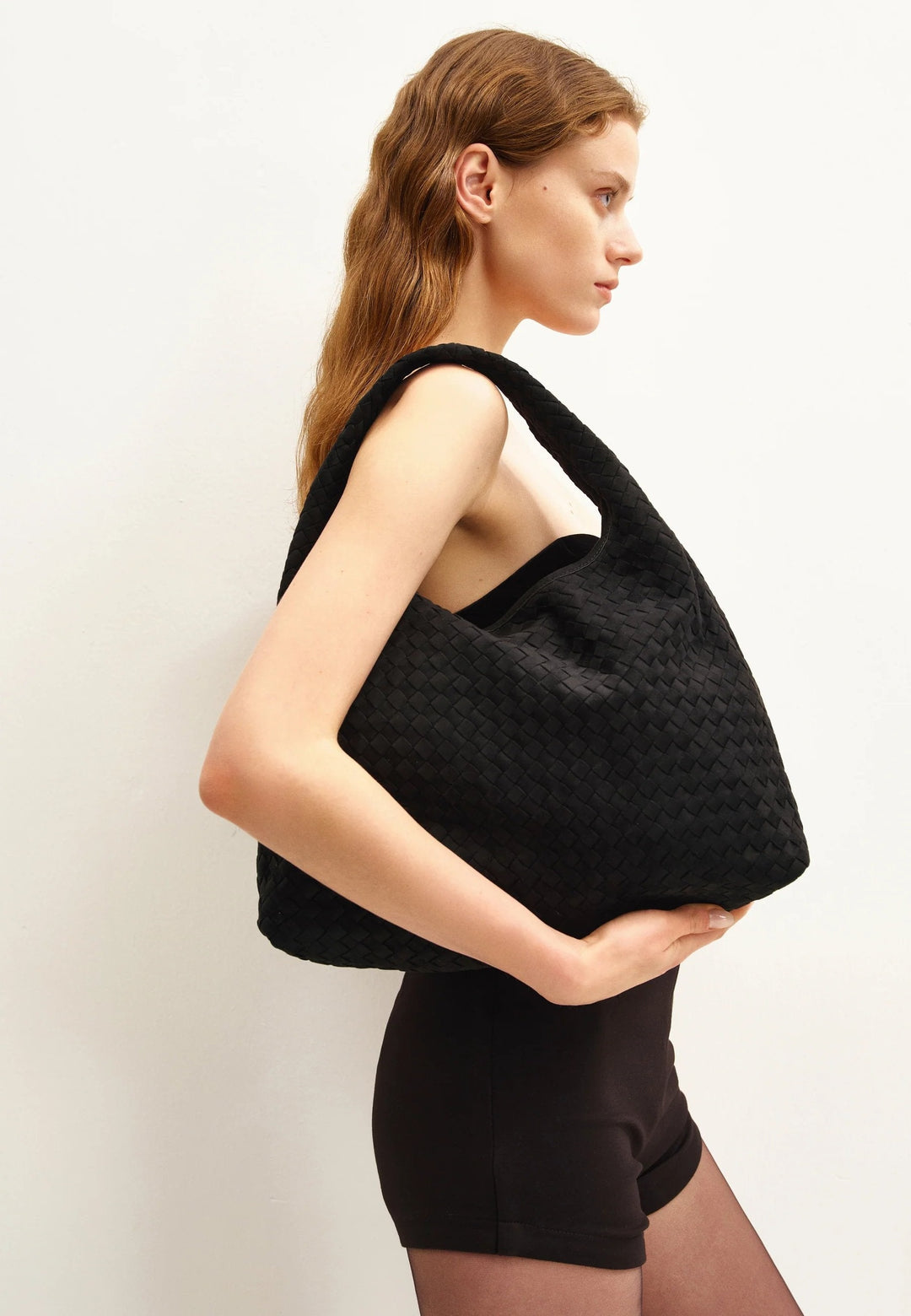 Sac bandoulière JW PEI Laura noir porté en bandoulière par une femme, vue de profil gauche