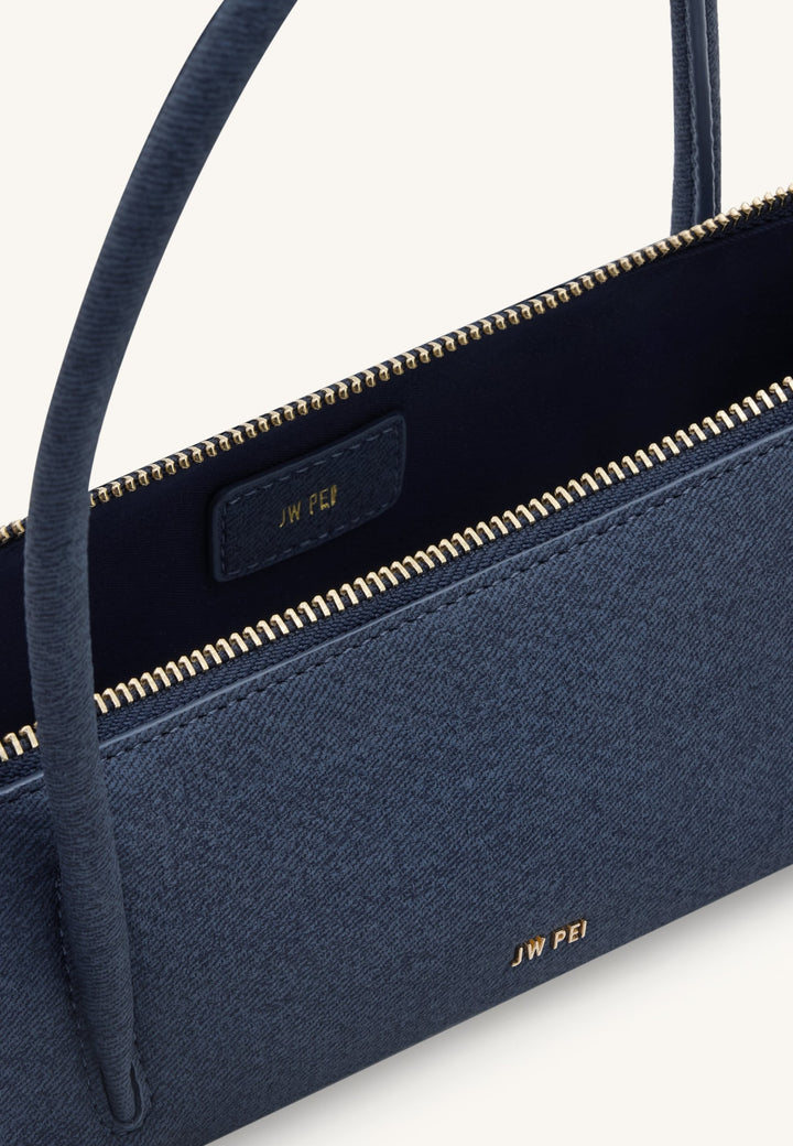 Intérieur d'un sac bandoulière JW PEI Nova bleu denim, montrant la fermeture éclair dorée et le logo de la marque