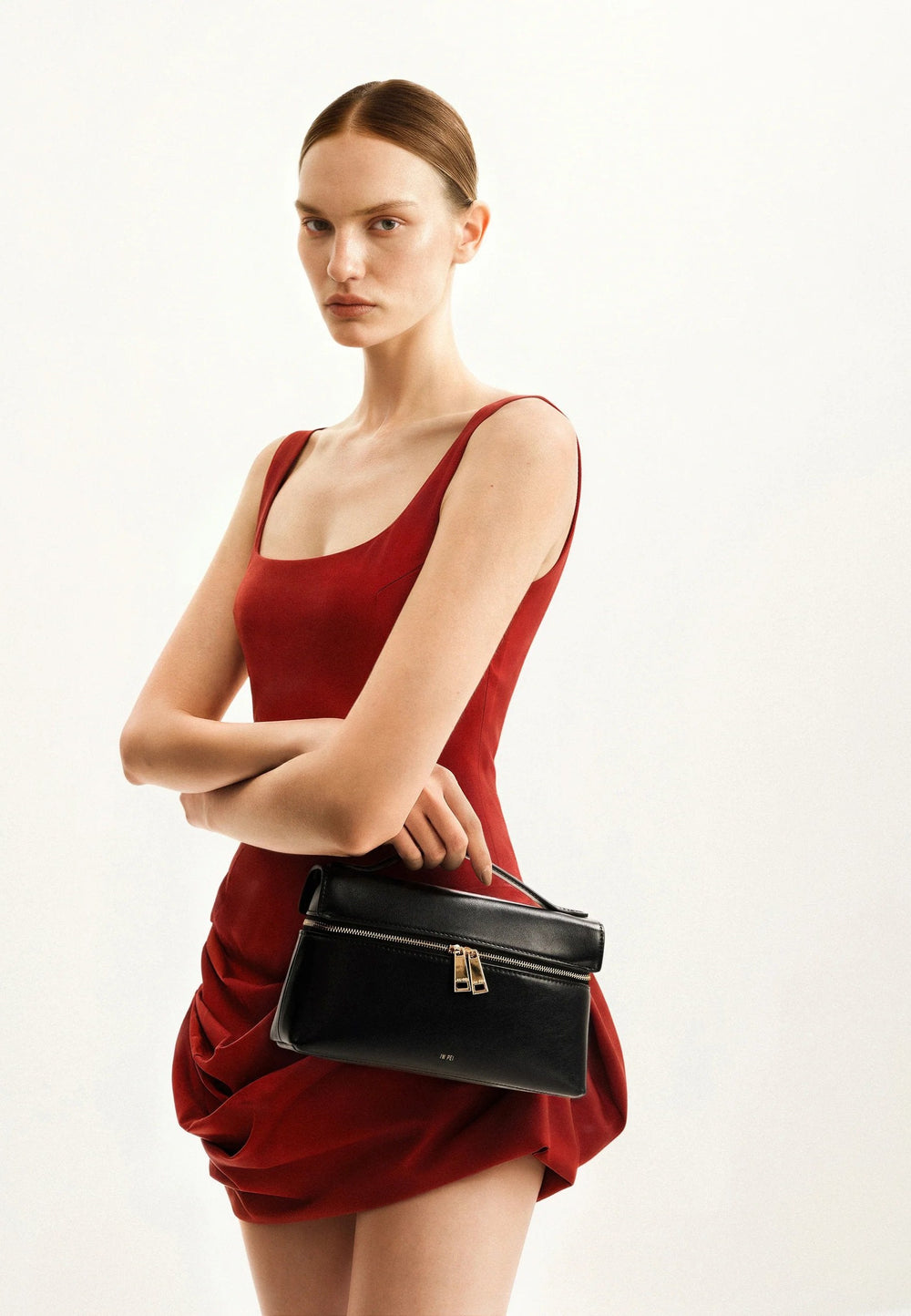 Sac à main JW PEI Thea noir, porté à la main, avec fermeture zippée dorée et logo discret.
