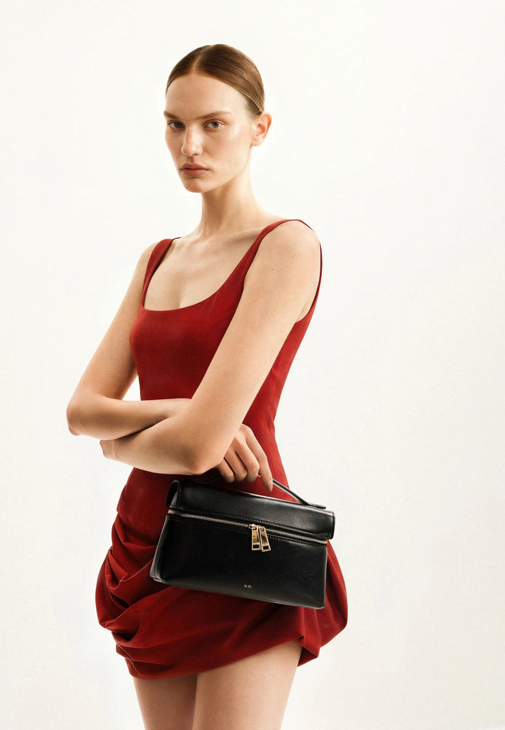 Sac à main JW PEI Thea noir, porté à la main, avec fermeture zippée dorée et logo discret.