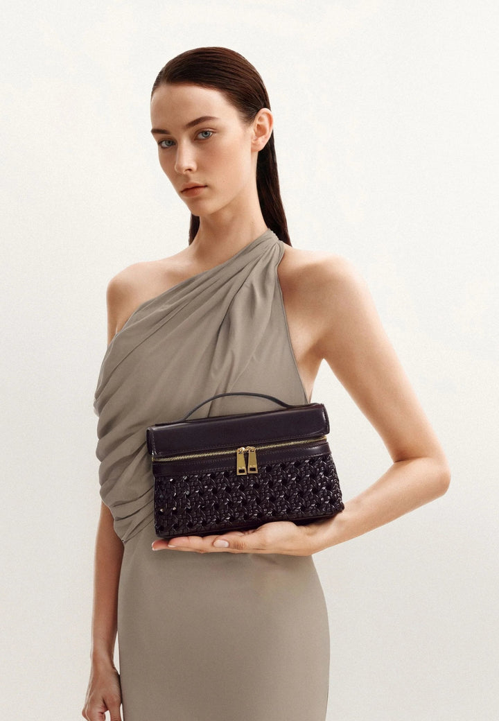 Sac à main JW PEI Thea Deep Claret porté à la main, avec une texture tressée et une fermeture zippée dorée.