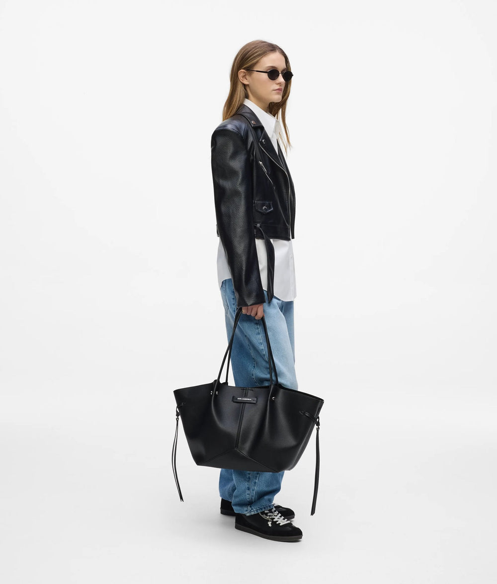 Karl Lagerfeld Le Ballet-Shopper a schwaarz, an der Hand gehalen, mat schwaarzem Jackett, wäissem Hiem a bloe Jeans.