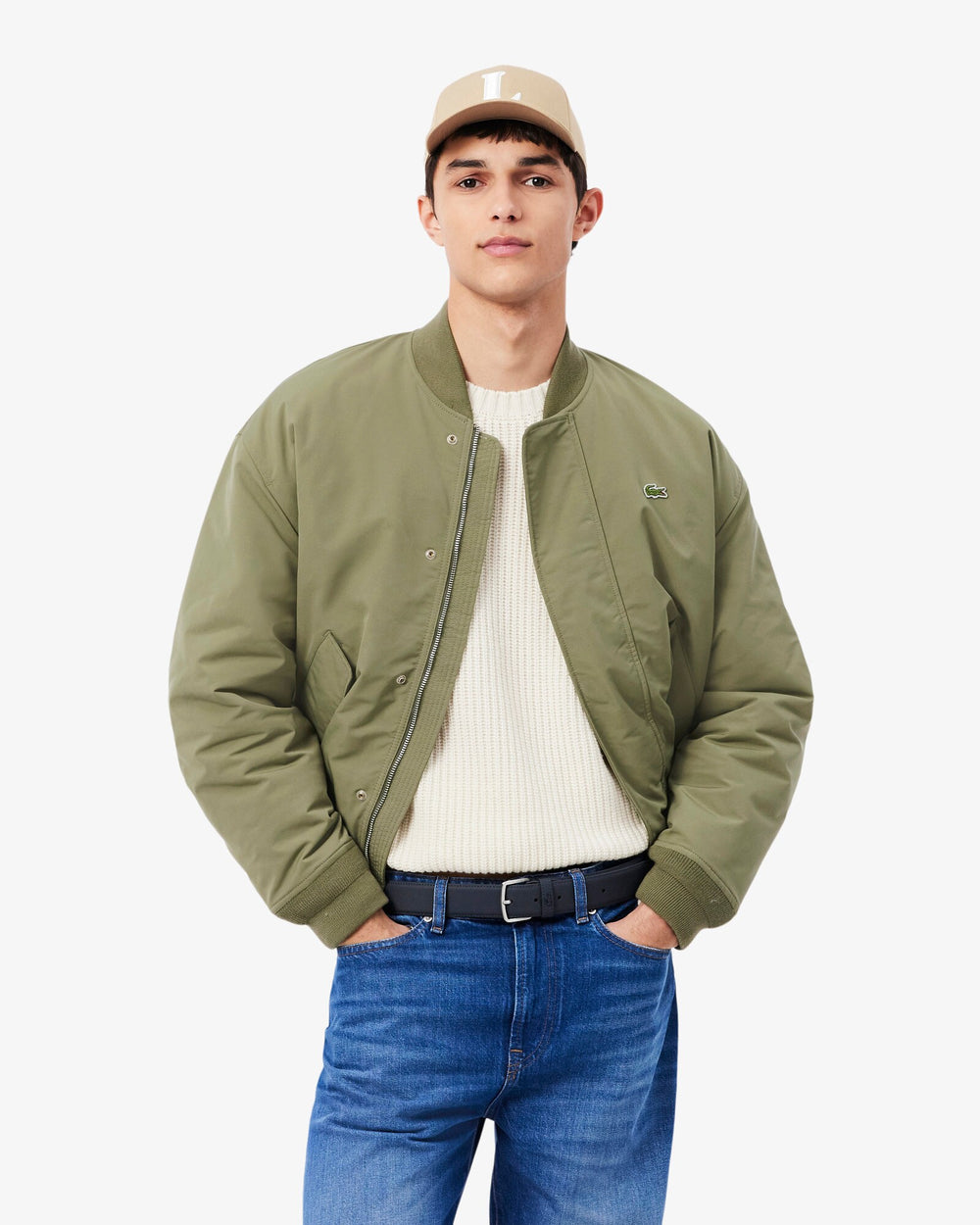 Lacoste modra torba Core Collection, nošena v pasu s kaki jakno, belim puloverjem in modrimi kavbojkami.