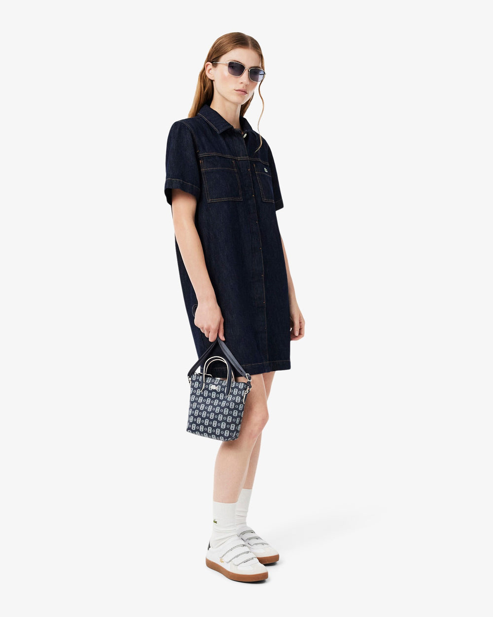 Lacoste shopper L.12.12 Concept blu tenuta a mano, con abito chemisier blu scuro e sneakers bianche.