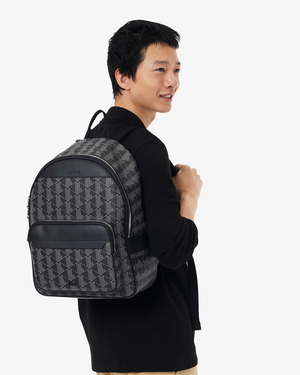 Lacoste czarny plecak Men’s Classic noszony na plecach, z czarną kurtką i czarnymi spodniami.