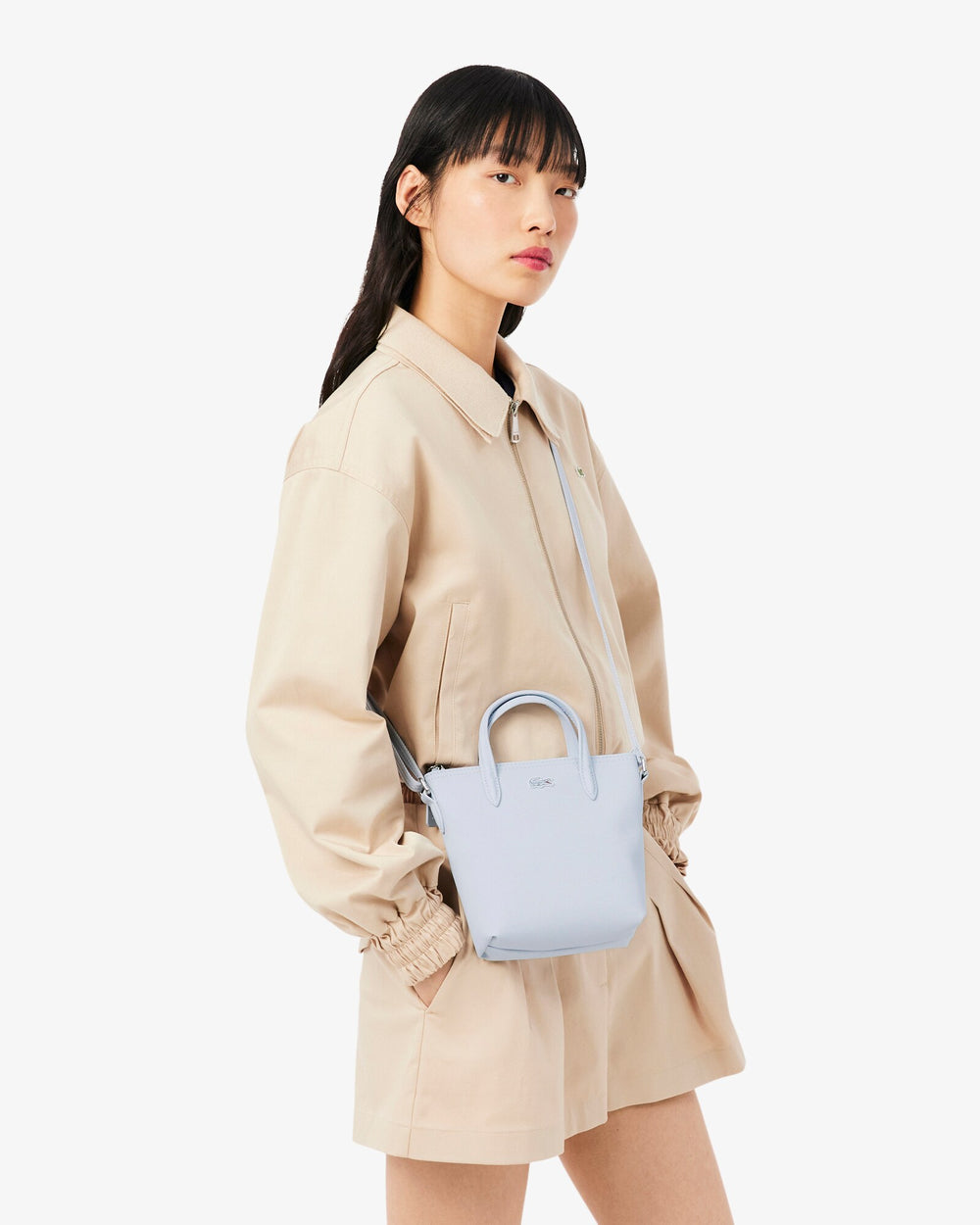 Lacoste cabas L.12.12 Concept bleu porté en bandoulière avec un ensemble beige.
