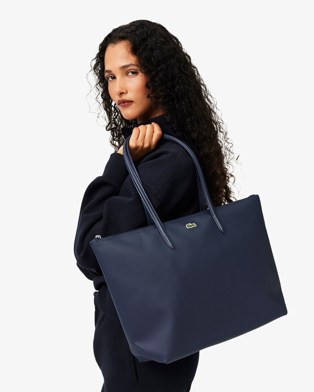 Lacoste modrá nákupná taška L.12.12 Concept cez plece k čiernemu oblečeniu.