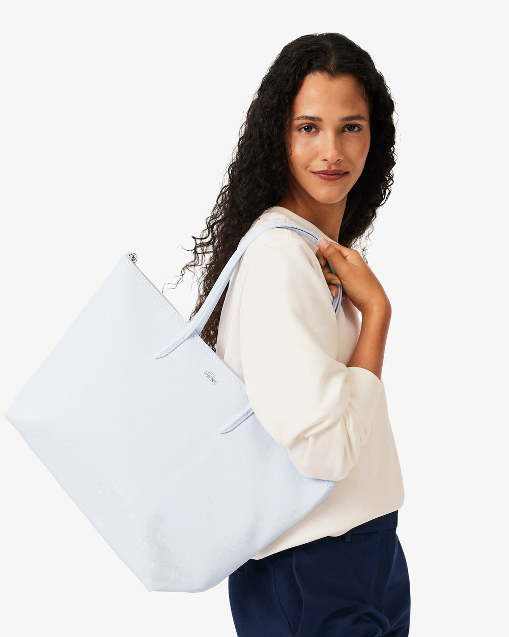 Lacoste modrá nákupná taška L.12.12 Concept na pleci, s bielym vrškom a tmavomodrými nohavicami.