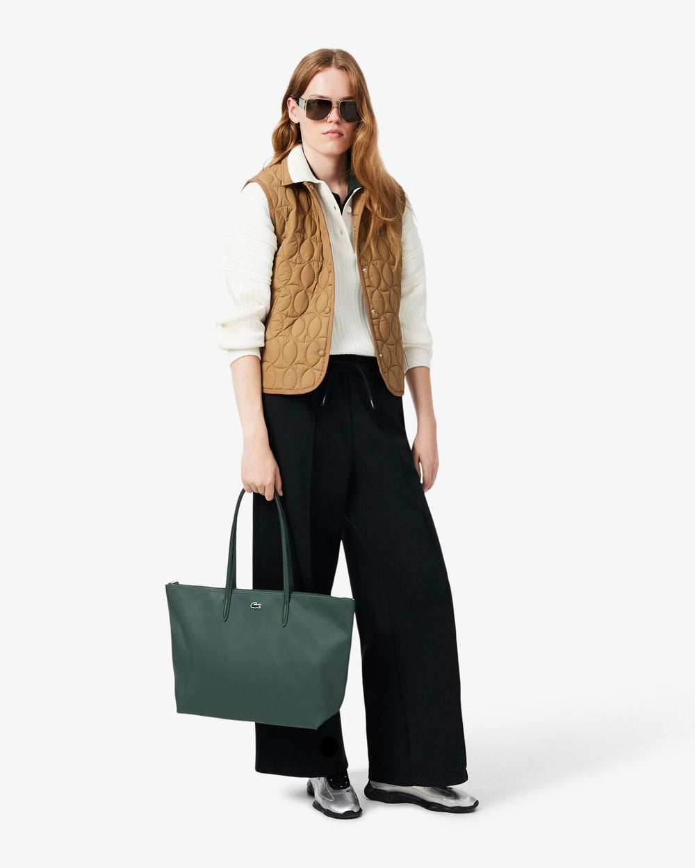 Lacoste nákupná taška L.12.12 Concept zelená, nesená v ruke, s béžovou vestou, bielou košeľou a čiernymi nohavicami.