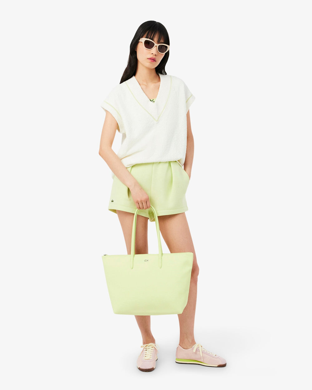 Lacoste zelená nákupná taška L.12.12 Concept držaná v ruke, k bielemu topu a svetlozelenej sukni.