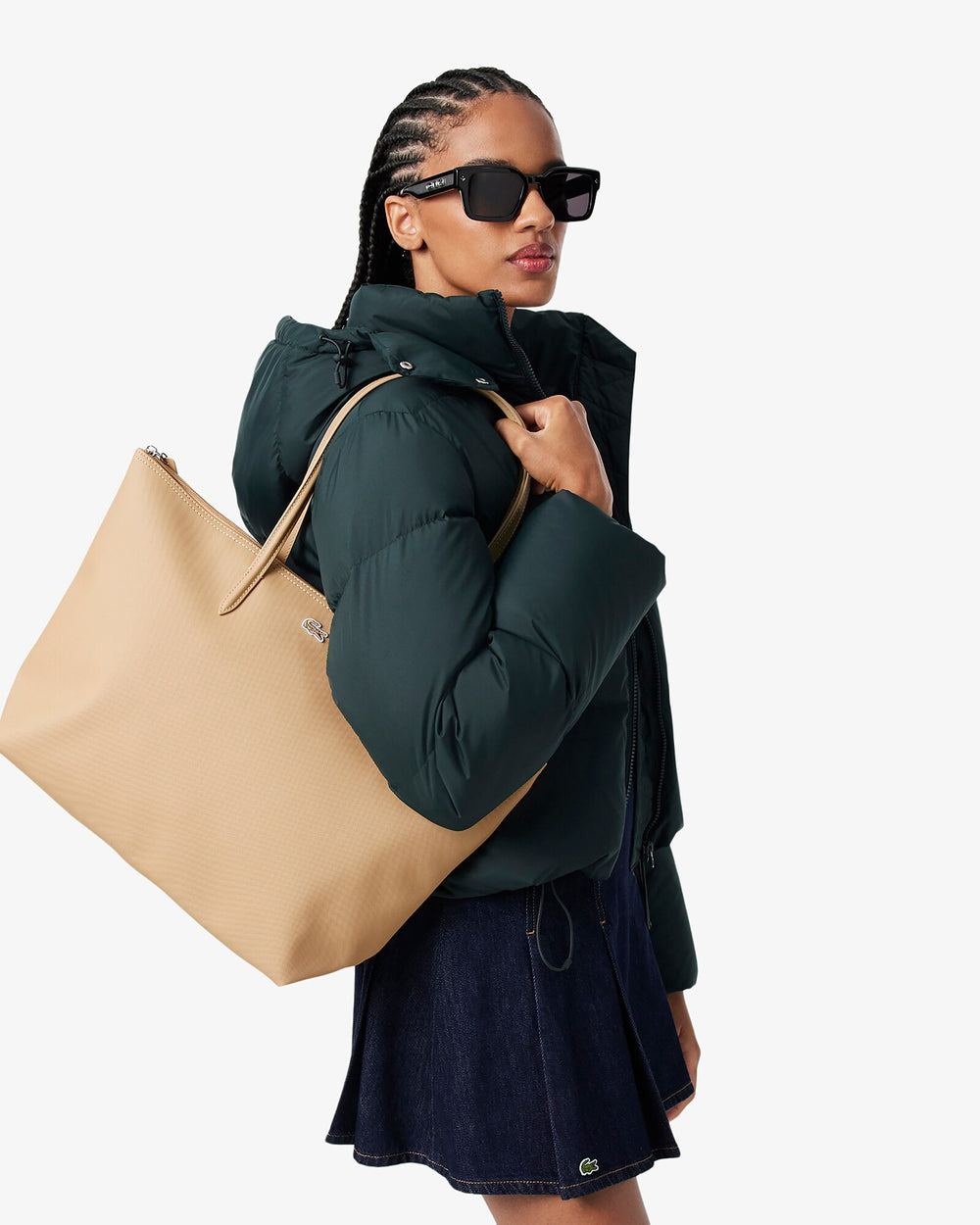 Lacoste hnedá nákupná taška L.12.12 Concept na pleci, k tmavozelenej prešívanej bunde a tmavomodrej sukni.