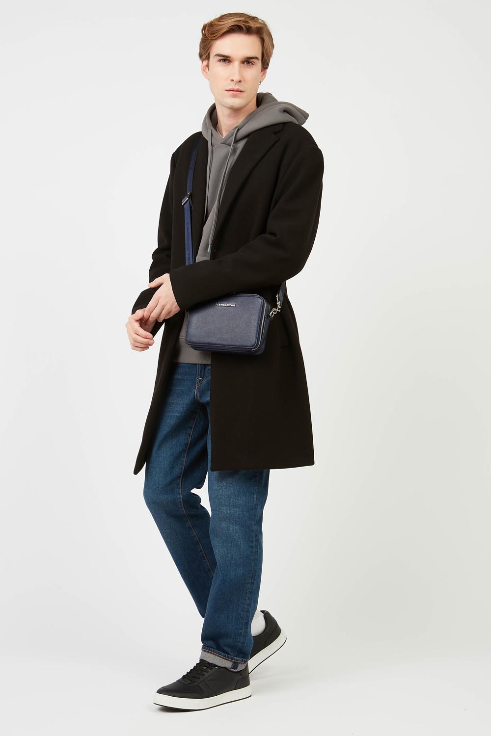 Lancaster Mala Tiracolo Double Zip Delphino S Verde Escuro – A mala Camera Delphino Lucas azul, usada a tiracolo, combina com um casaco preto e umas calças de ganga azuis.