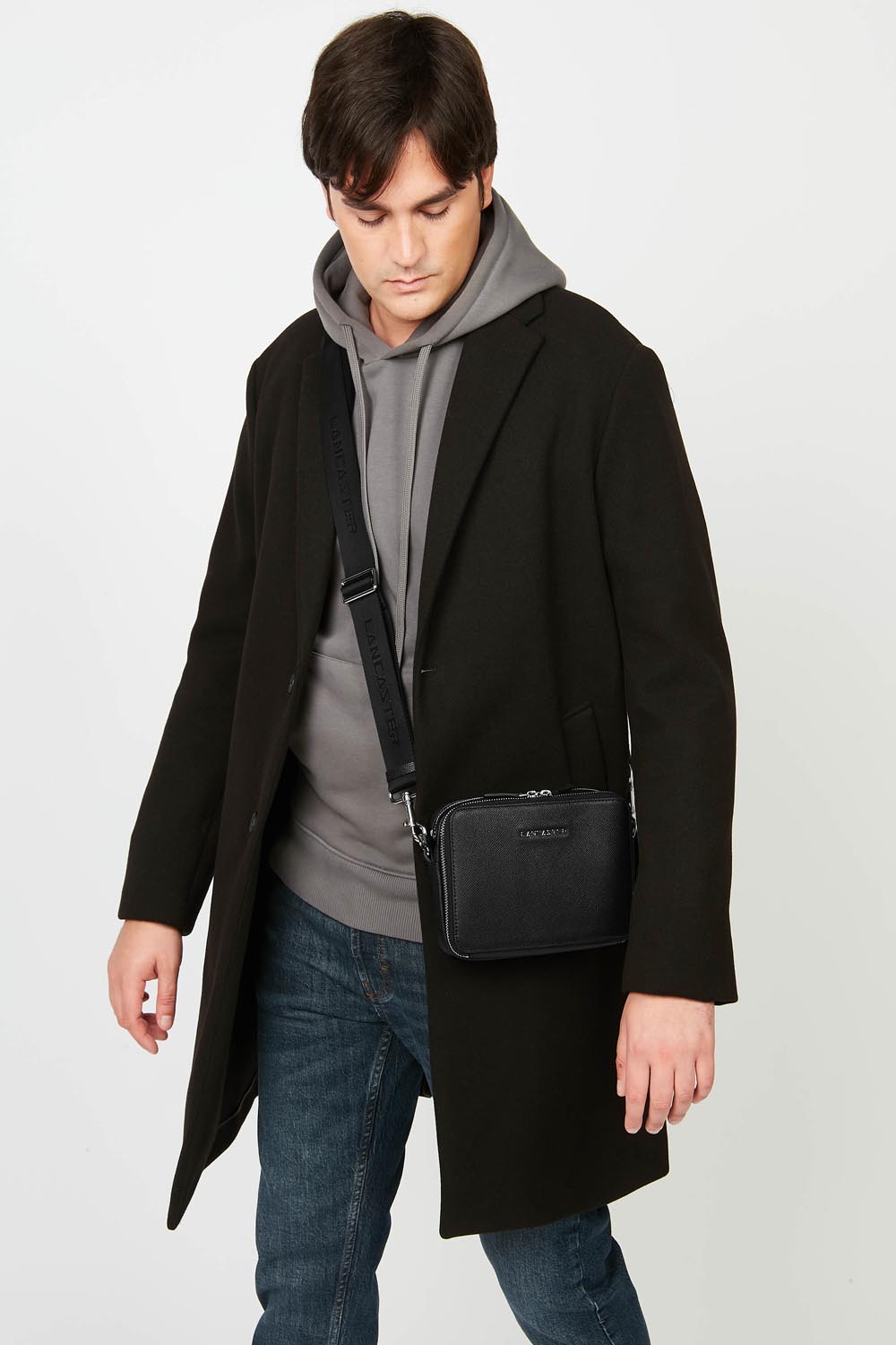 Lancaster Mala Tiracolo Double Zip Delphino S Verde Escuro – Com um casaco preto e uma camisola cinzenta, a mala Camera Delphino Lucas usa-se a tiracolo.
