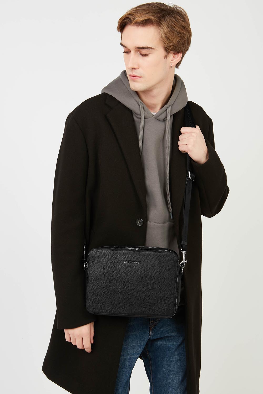 Lancaster Sacoche Homme Cuir Delphino Lucas Noir – En bandoulière, le sac Camera Delphino Lucas complète un manteau noir et un sweat gris.