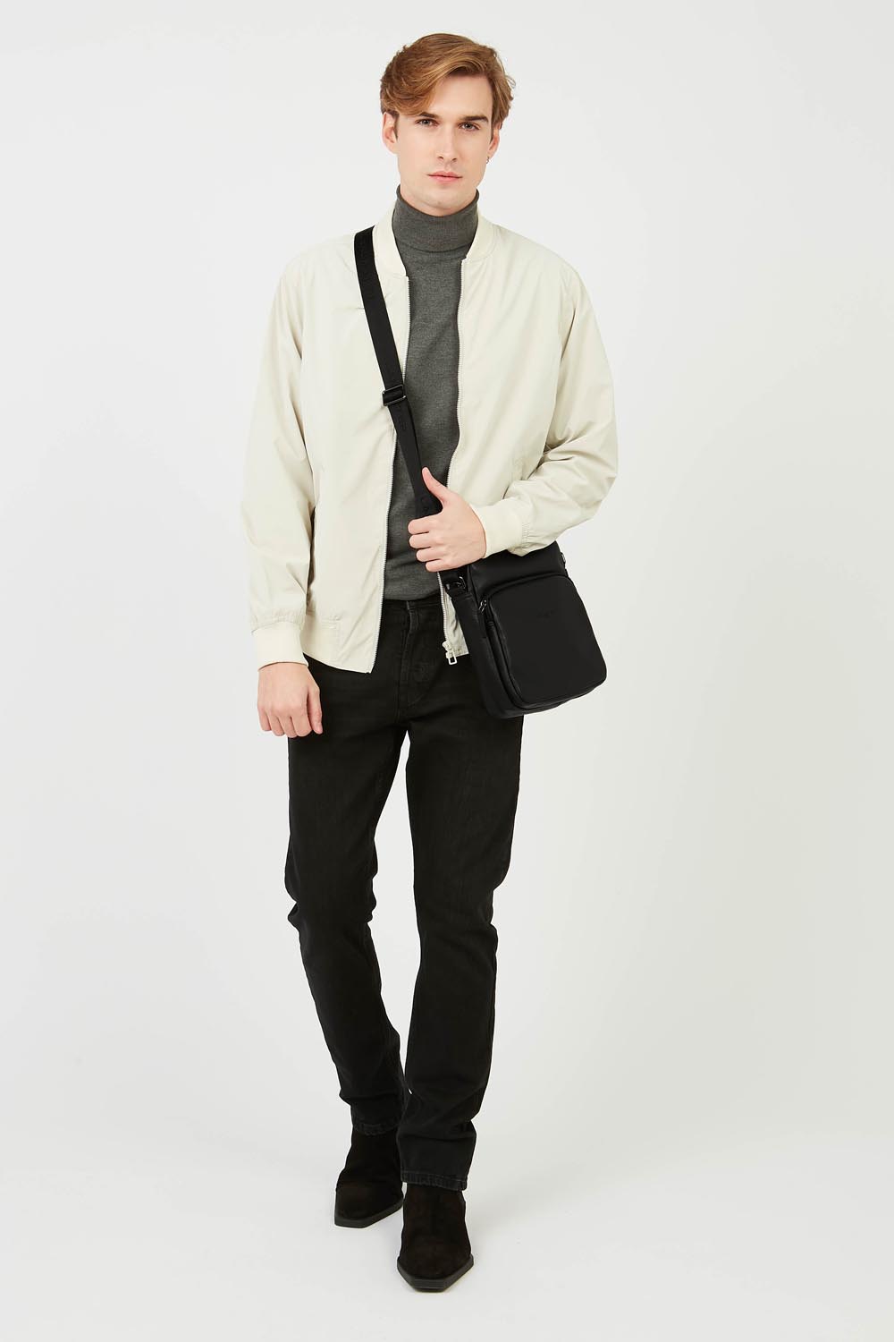 Lancaster besace Soft Vintage noire portée en bandoulière avec une tenue composée d’un haut clair et d’un pantalon noir.