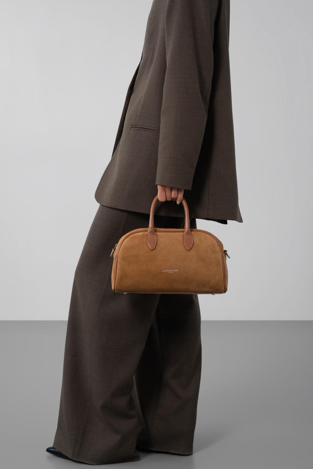 Lancaster, brown Bowling bag held by hand with a matching coat and wide-leg trousers.