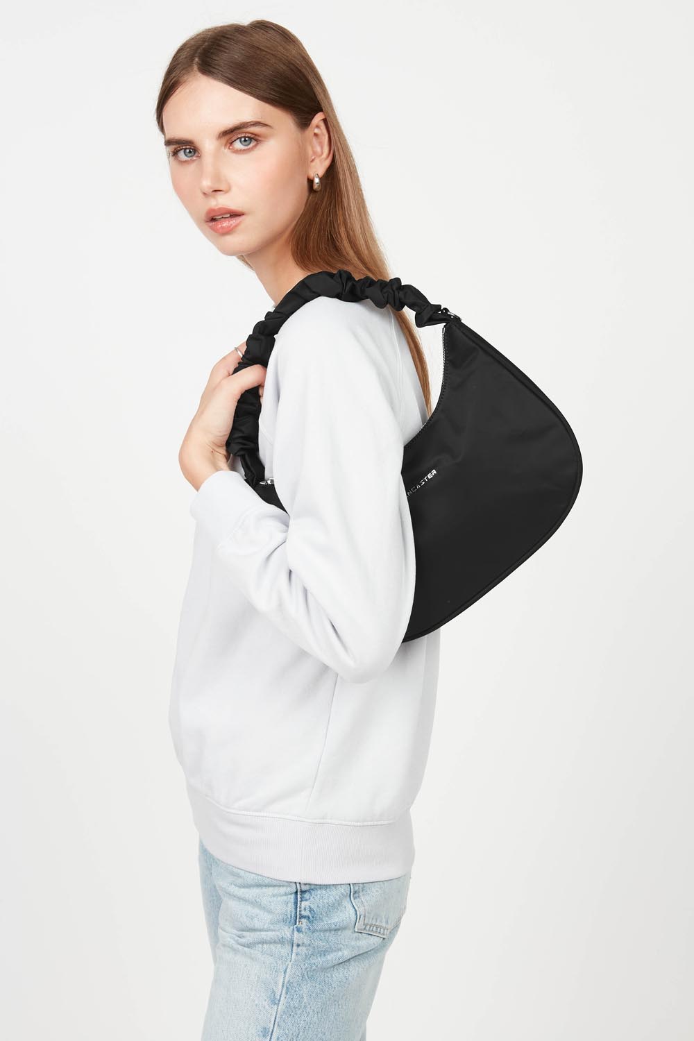 Lancaster, mala hobo Basic Chouchou preta ao ombro, com uma peça branca e calças de ganga azul-claro.
