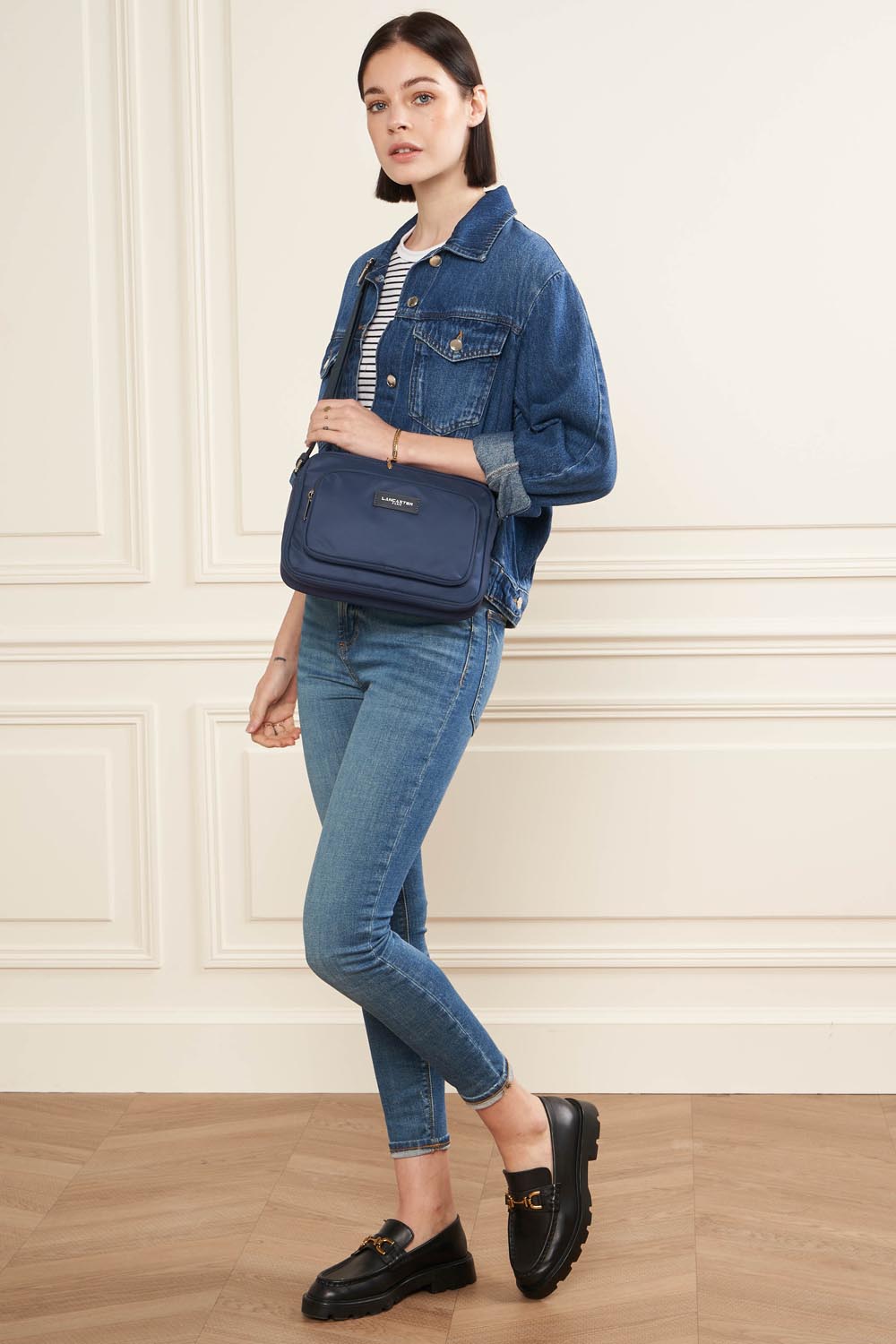 Lancaster Zipped Crossbody Bag Basic Vita Atoll Blue – In navy blue, the Basic Vita trotteur is carried over the shoulder with a denim jacket and blue jeans.