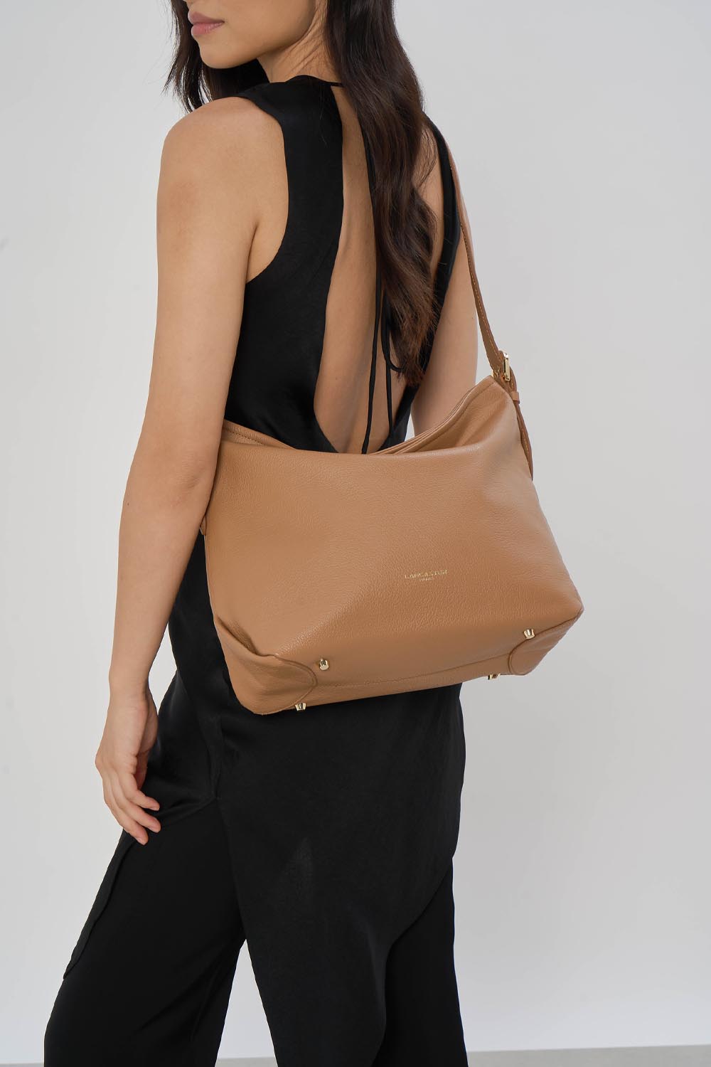 Lancaster Borsa a secchiello con zip Dune Blu – La borsa a secchiello Dune è portata a spalla con una tuta nera senza maniche.