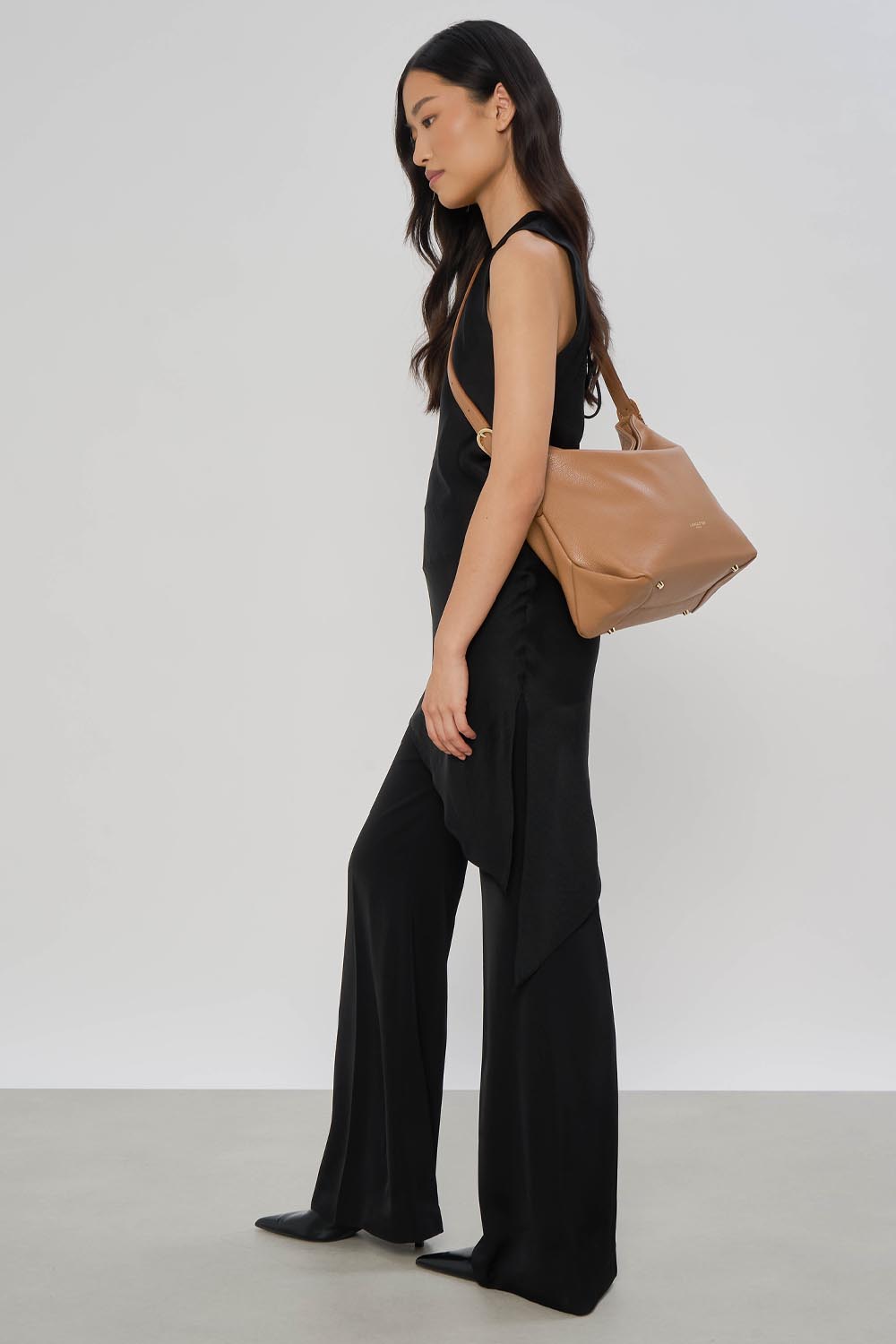 Lancaster Borsa a secchiello con zip Dune Blu – Top nero e pantaloni fluidi per la borsa a secchiello Dune marrone, portata a spalla.