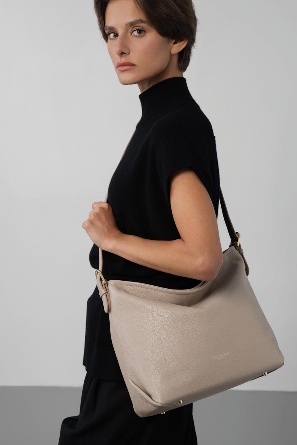 Lancaster Borsa a secchiello con zip Dune Blu – A spalla, la borsa a secchiello Dune completa un top nero a maniche corte e pantaloni neri.
