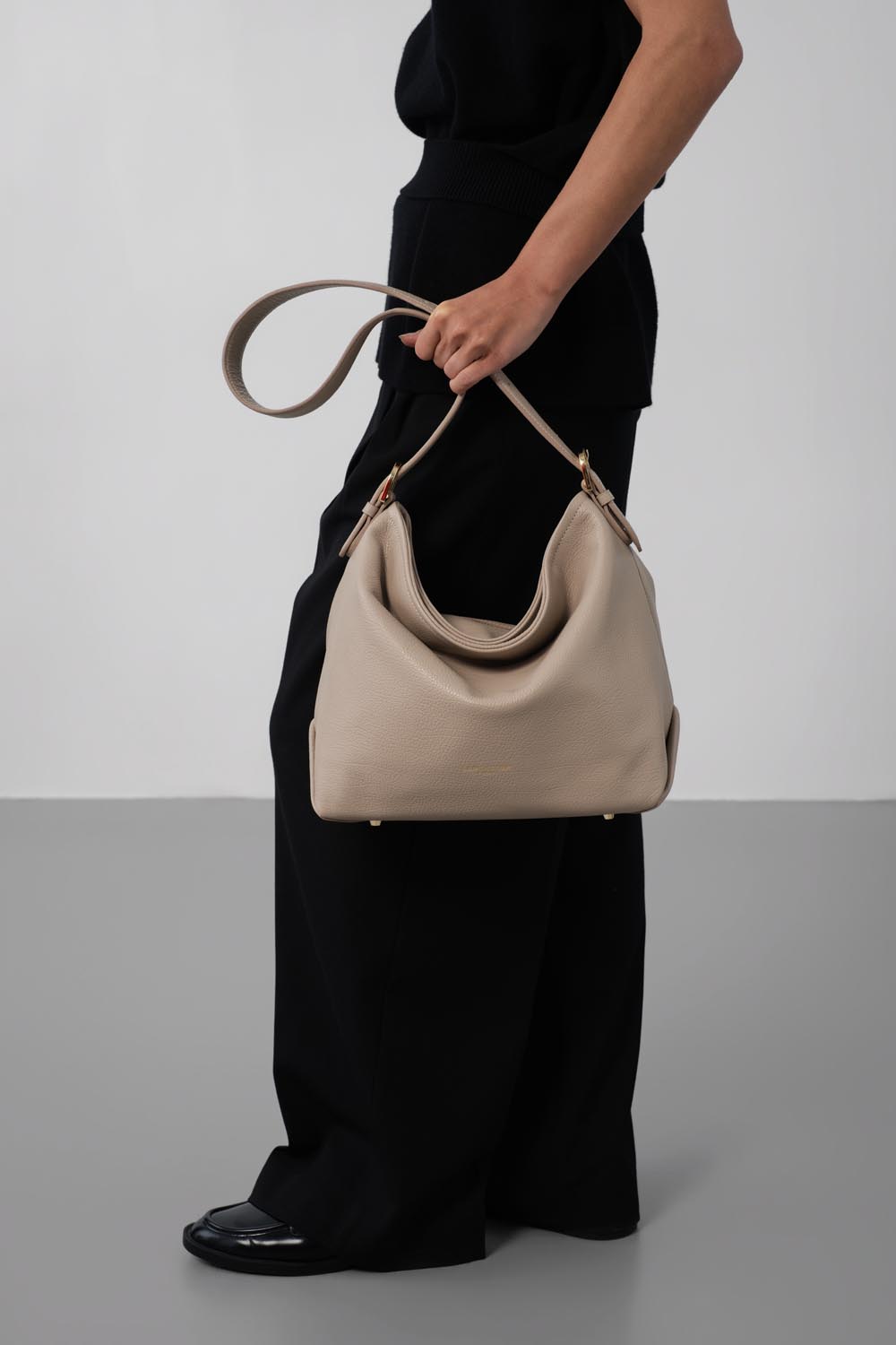 Lancaster Borsa a secchiello con zip Dune Blu – Outfit nero e scarpe coordinate per la borsa a secchiello Dune, portata a mano.