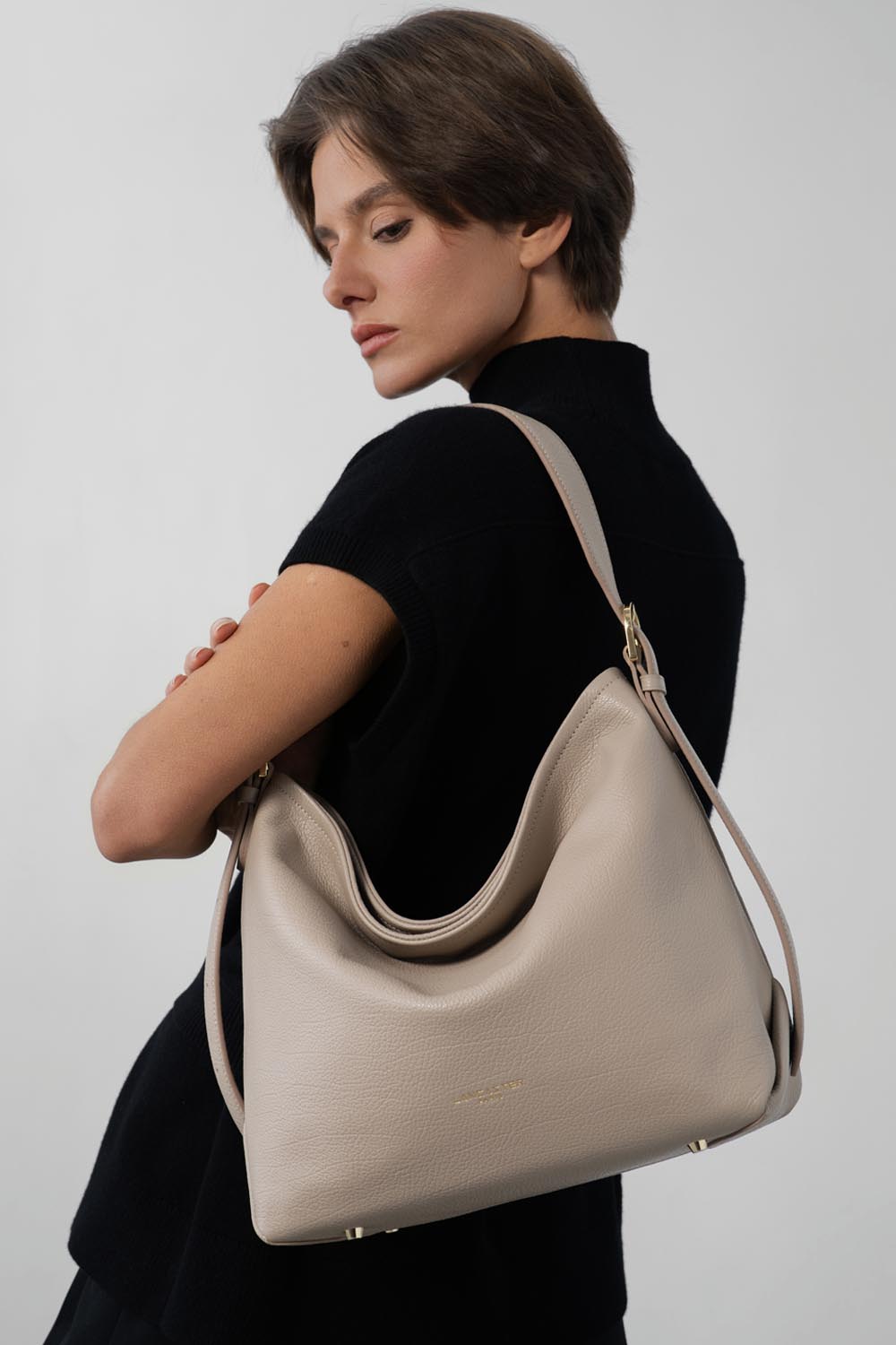Lancaster Borsa a secchiello con zip Dune Blu – Top nero e pantaloni neri per la borsa a secchiello Dune portata a spalla.