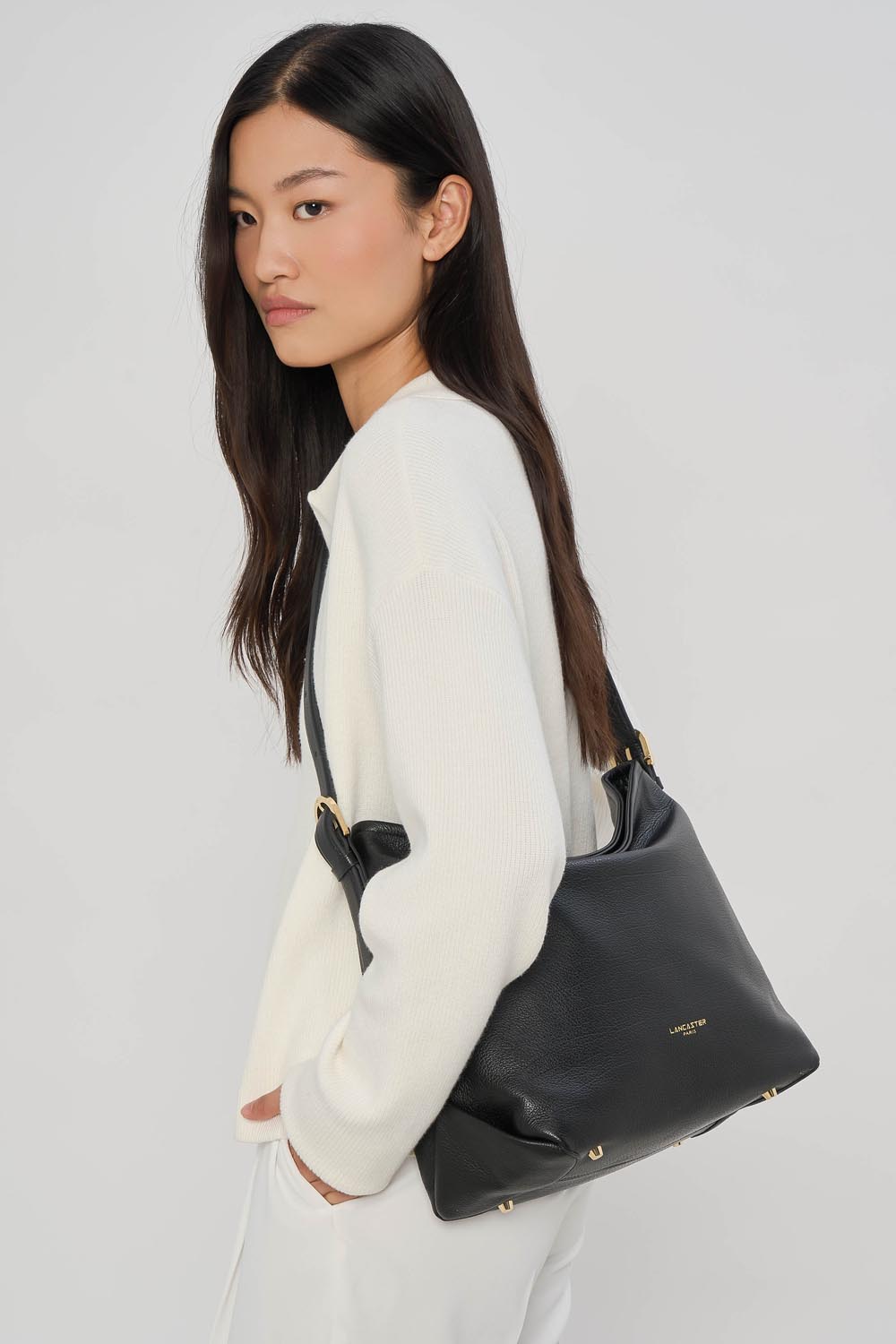 Lancaster Borsa a secchiello con zip Dune Blu – La borsa a secchiello Dune nera a spalla si abbina a un top bianco e a pantaloni bianchi.
