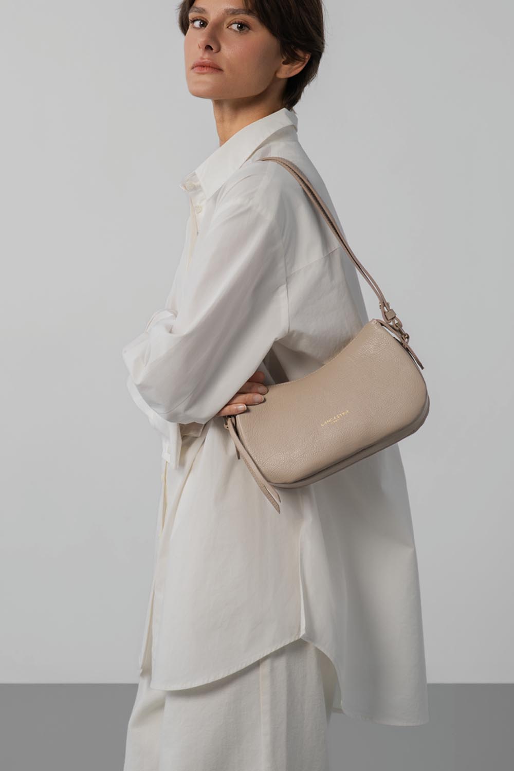 Lancaster Borsa a tracolla S Dune Beige Scuro – In beige, la borsa a tracolla Dune si porta a spalla con una lunga camicia bianca e pantaloni coordinati.