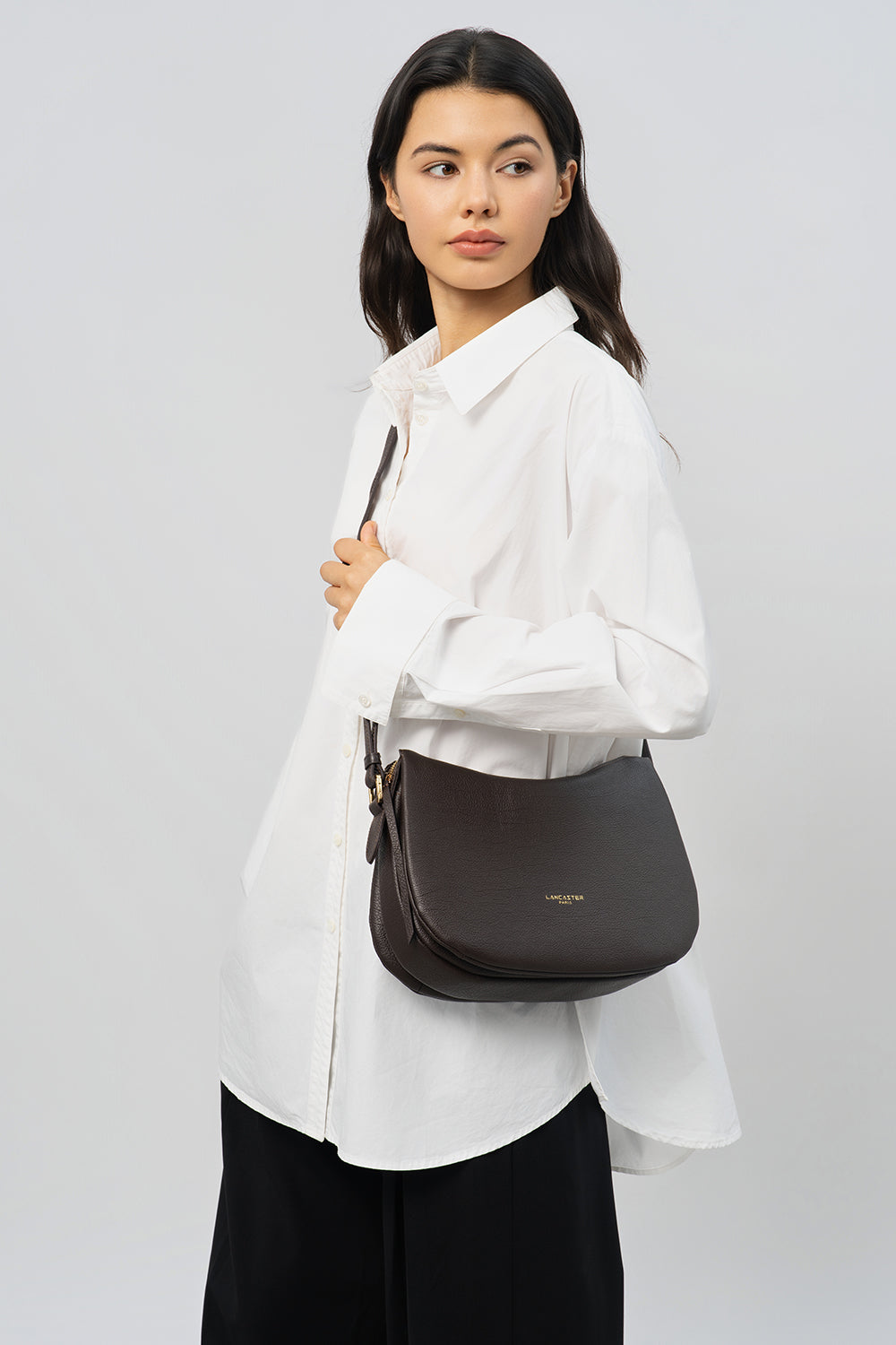 Lancaster Borsa a tracolla Con zip M Dune Camel – Camicia bianca e pantaloni neri per la borsa Dune portata a spalla.