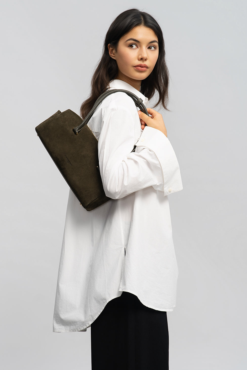 Lancaster Rectangle Bag Zippered Suède Cube Brown – The rectangular bag sits over the shoulder with a loose white shirt and black trousers.