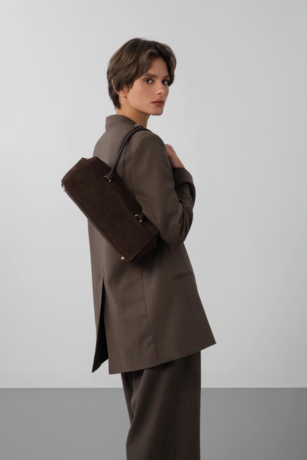 Lancaster Rectangle Bag Zippered Suède Cube Brown – Brown jacket and trousers with this rectangular bag carried over the shoulder.