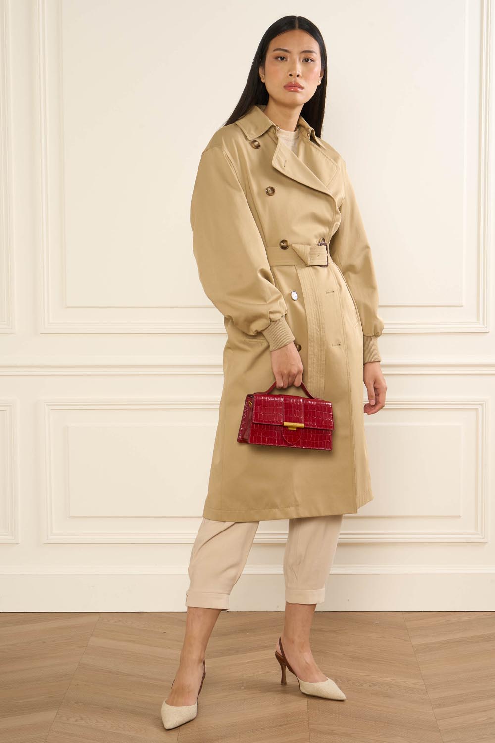 Lancaster Baguette-Tasche Exo Ily M Schwarz Krokoprägung – Die rote Baguette Exo Ily in der Hand setzt einen beigen Trenchcoat und eine cremefarbene Hose in Szene.