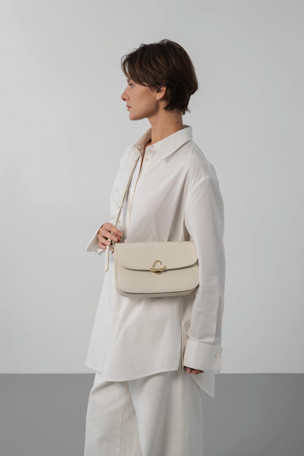 Lancaster Sac trotteur à rabat aimanté Paris Philos Noir – Mat enger wäisser Blouse an enger passender Box gëtt den Trotteur Paris Philos iwwer der Schëller gedroen.