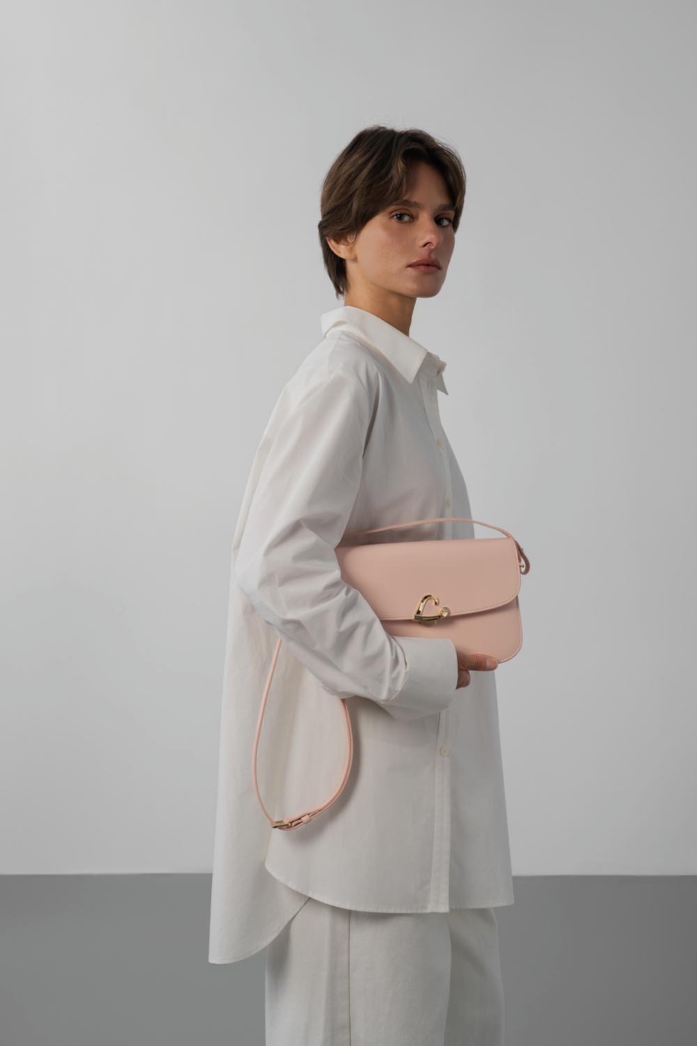 Lancaster Sac trotteur à rabat aimanté Paris Philos Noir – D’Trotteur-Täsch Paris Philos gëtt virun engem wäissen Hiem an enger hellfarweger Box an der Hand gehalen.