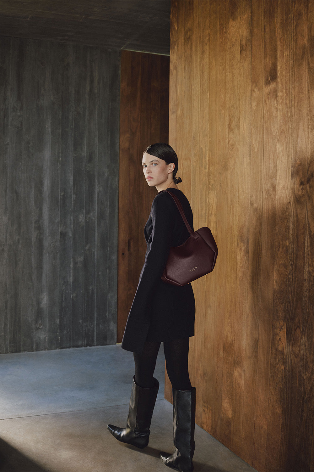 Lancaster Bolso Tote Sierra Haus Caqui – Llevado al hombro, el bolso acompaña un vestido negro, medias y botas negras.