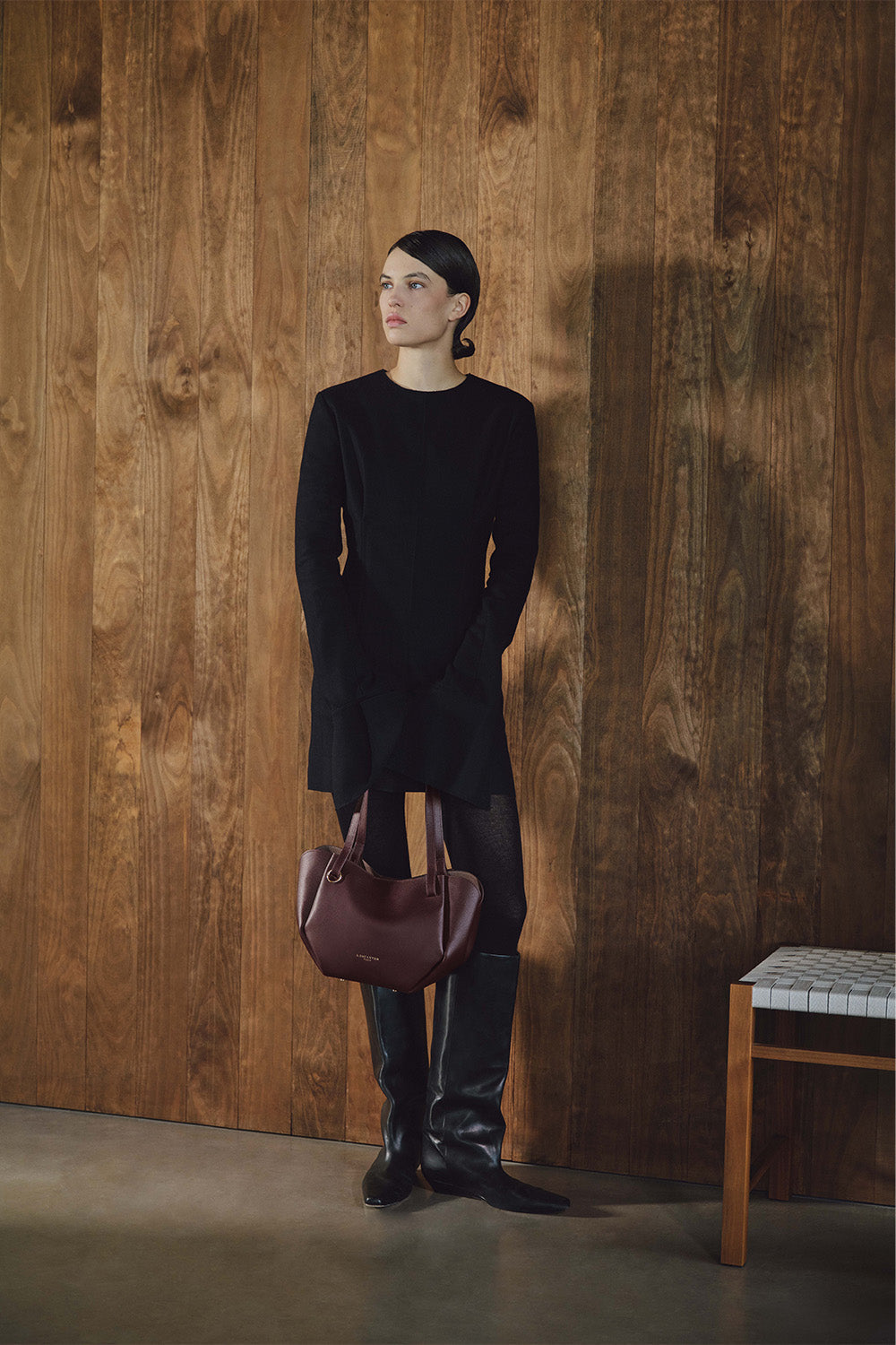 Lancaster Bolso Tote Sierra Haus Caqui – Llevado en la mano, el bolso acompaña un vestido negro y unas botas negras.