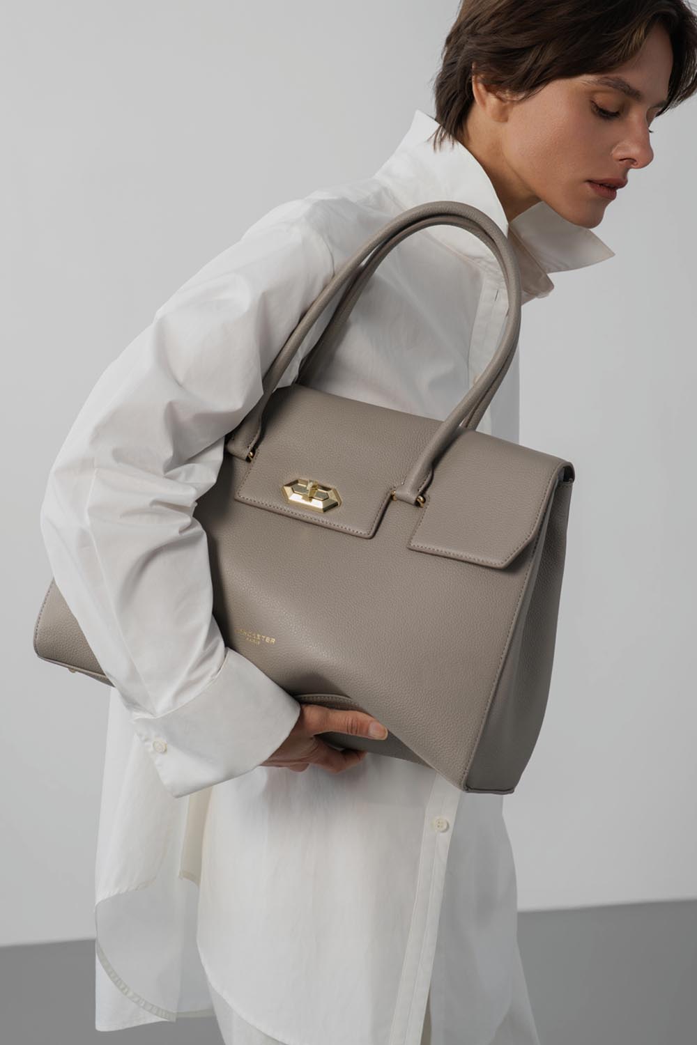 Lancaster Borsa Shopper Foulonné Milano XL Champagne – La borsa tote grigia è tenuta a mano con una camicia bianca ampia.