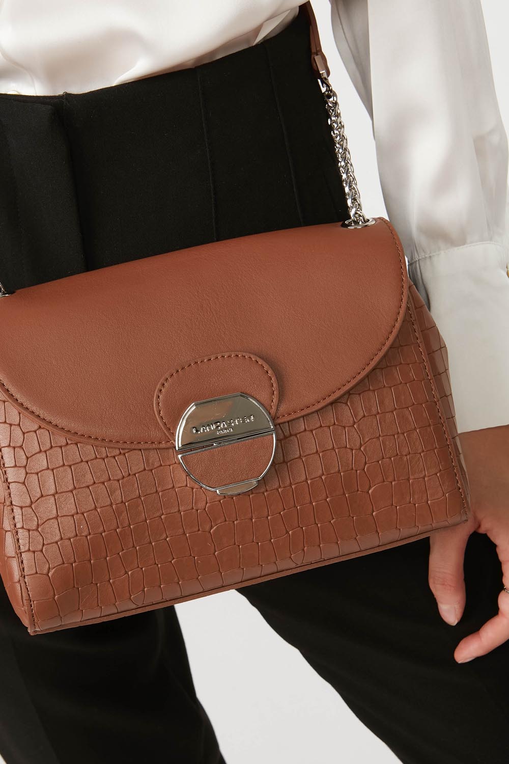 Lancaster Pia Camel Flap Crossbody Bag – White shirt and black trousers with the Pia satchel worn over the shoulder.