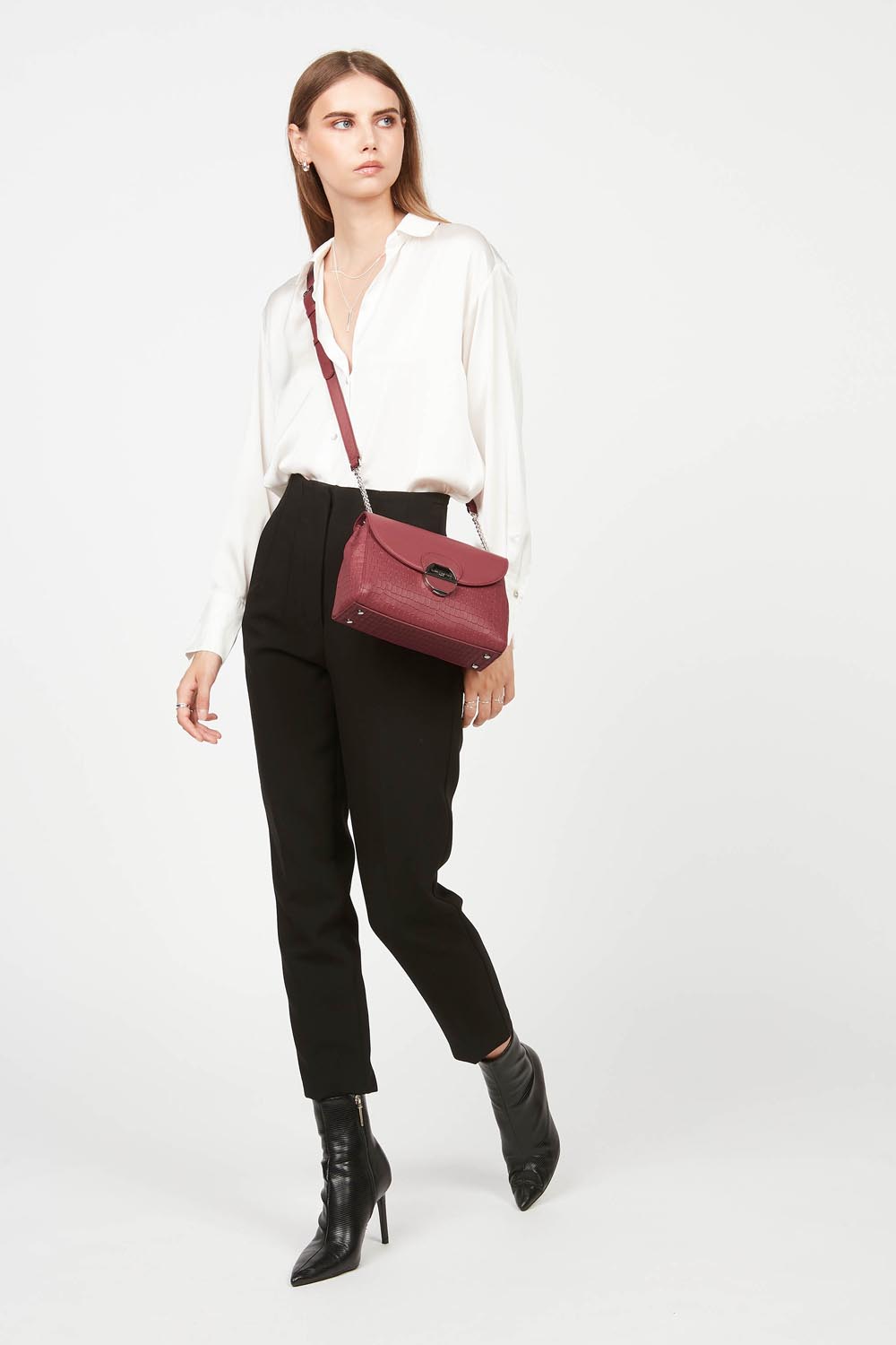 Lancaster Pia Camel Flap Crossbody Bag – The Pia trotteur bag is worn crossbody and pairs with a white blouse, black trousers and black ankle boots.