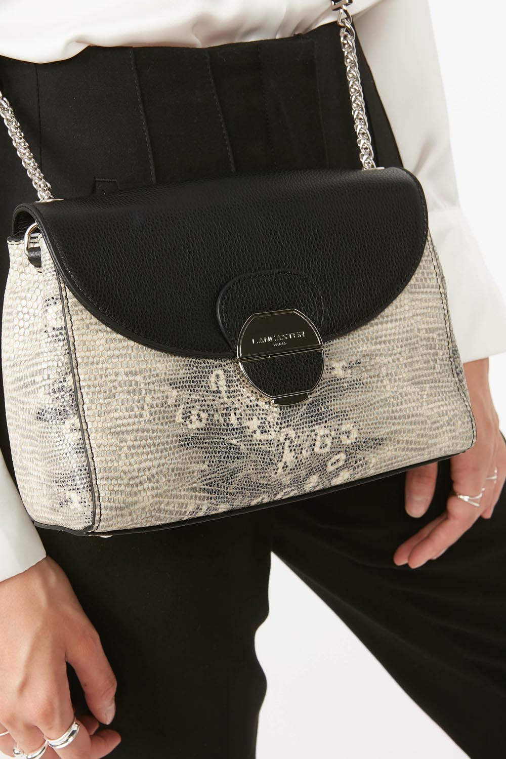 Lancaster Pia Camel Flap Crossbody Bag – With a white top and black trousers, the Pia Trotteur is worn over the shoulder.