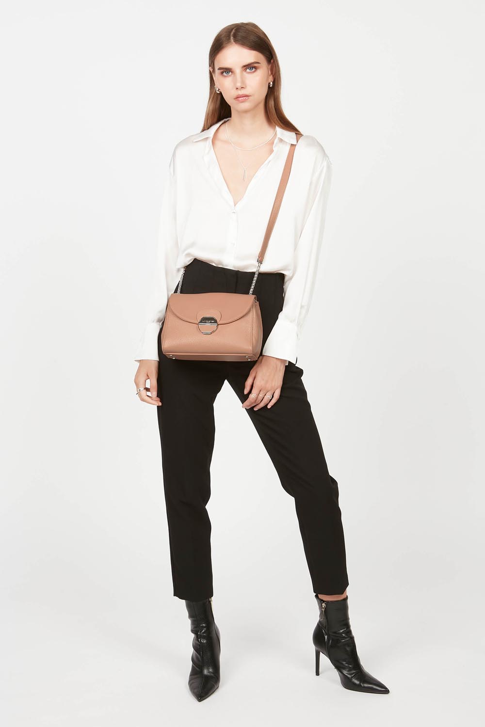 Lancaster Pia Camel Flap Crossbody Bag – The Pia Trotteur bag is worn crossbody with a white blouse, black trousers and black ankle boots.