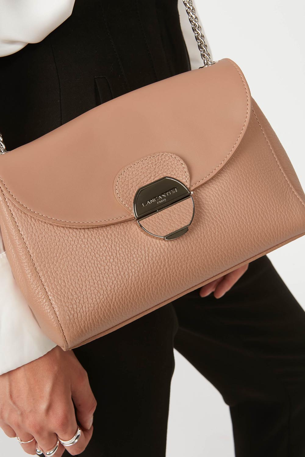 Lancaster Pia Camel Flap Crossbody Bag – Slung over the shoulder, the Pia trotteur pairs with a white top and black trousers.